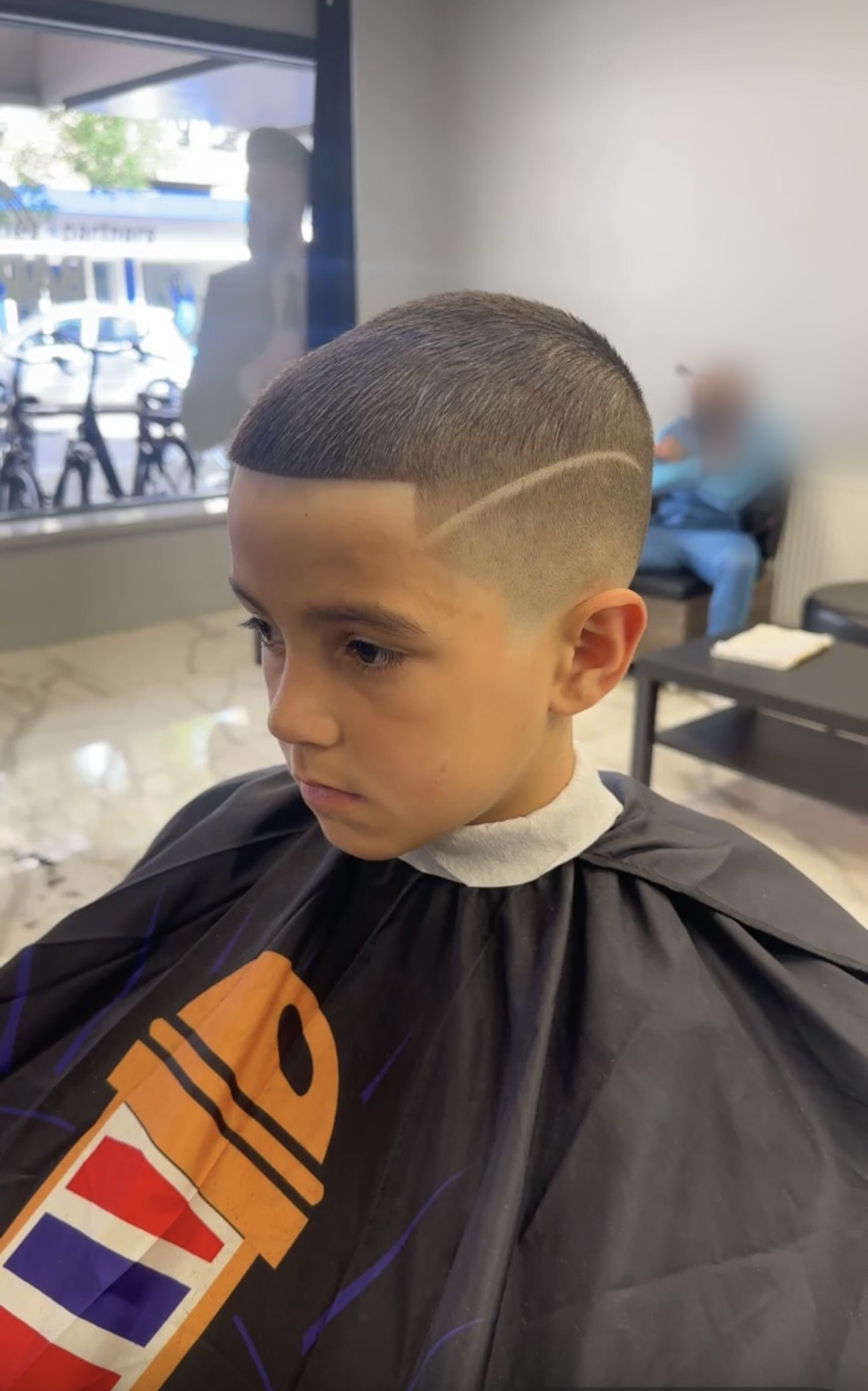 Jongen met een fade en een geschoren scheidingslijn, van opzij gezien
