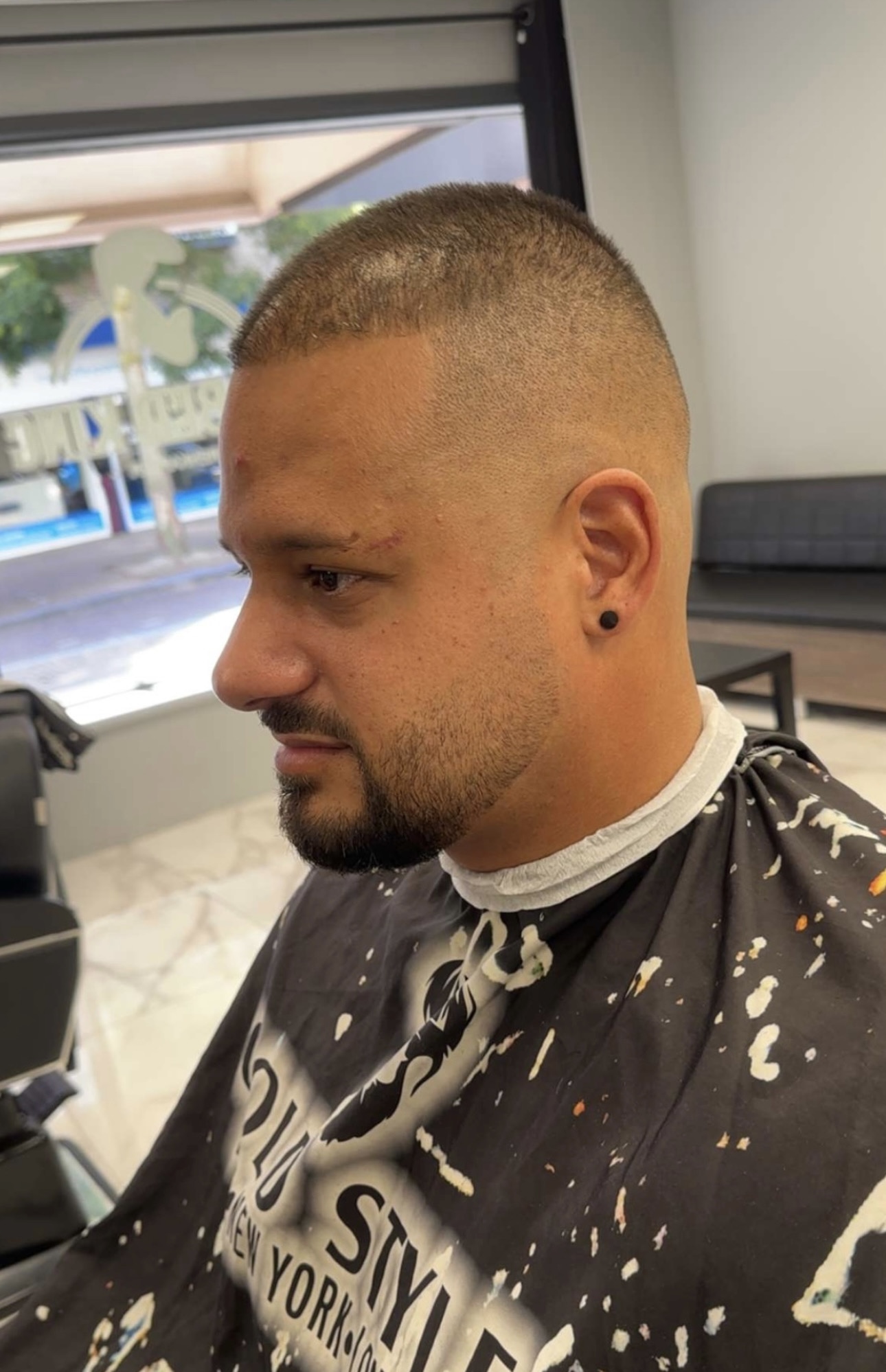 Klant met een skin fade en een kort bijgewerkte baard, van opzij gezien